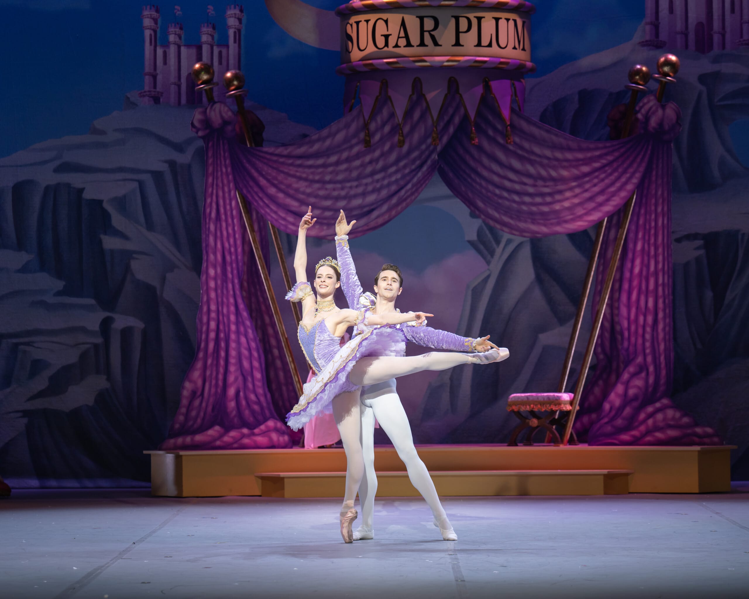 Two ballet dancers perform a graceful duet on stage in a scene from Nutcracker. The female dancer