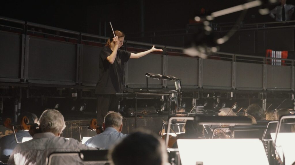A conductor leading an orchestra rehearsal